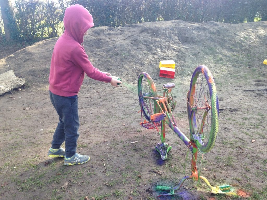 photo of child spray painting a bicycle